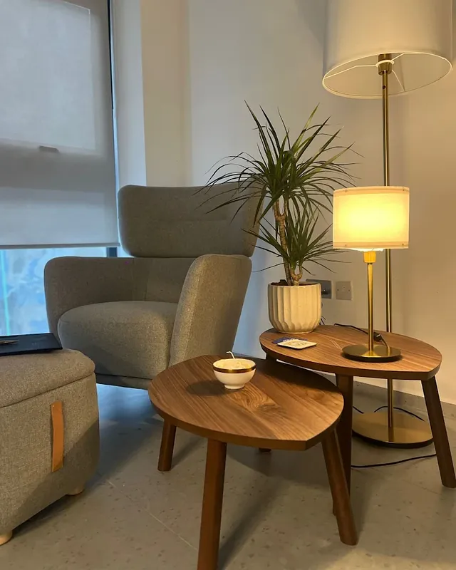 A therapy room with an armchair, side tables and warm lamps