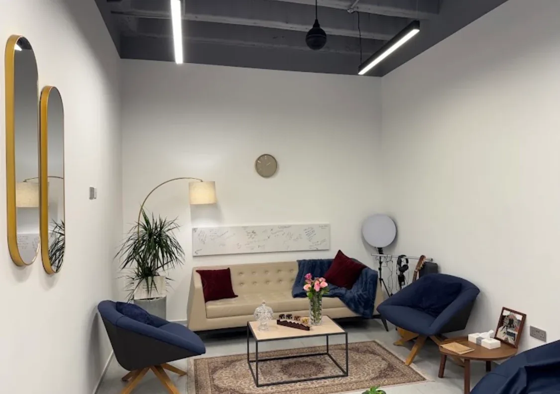 A relaxed room at the center with a sofa, armchairs, rug and floor lamp