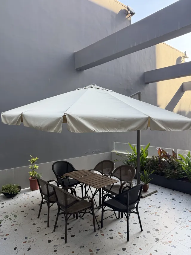 The outdoor terrace with a table, chairs, plants and a large umbrella